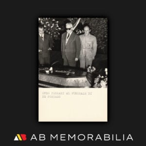 Enzo Ferrari, founder of Scuderia Ferrari, attending the funeral of Spanish racing driver Alfonso de Portago following the fatal accident during the Mille Miglia on 12 May 1957. The image captures Ferrari beside de Portago’s coffin, a moment marked by solemn reflection and public scrutiny in the aftermath of the tragedy. Original period press photograph of Enzo Ferrari at a historic moment in his career