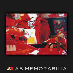 Michael Schumacher signed 2005 photograph seated in his Ferrari in the pits, with a bold black autograph across the upper portion. Perfect Michael Schumacher signature