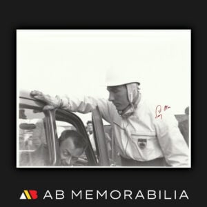 Original press photograph signed by Stirling Moss 1954 Silverstone wearing helmet and race suit with BRDC patch