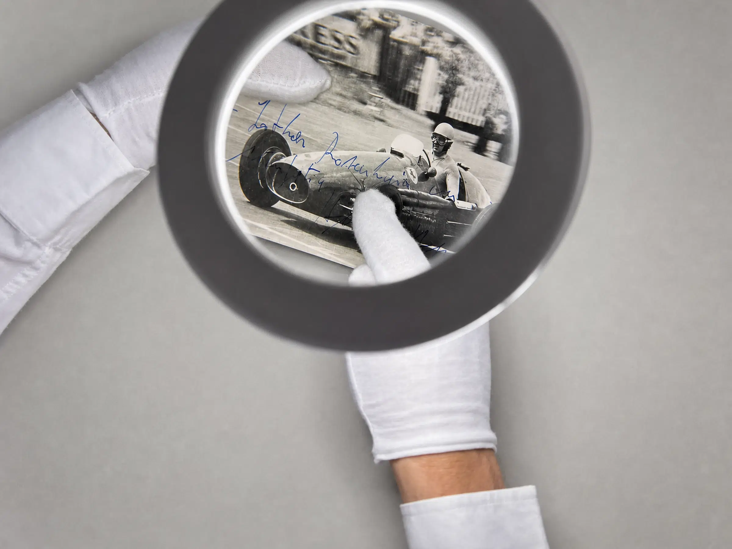 A signed vintage Formula One photograph examined under a magnifying glass