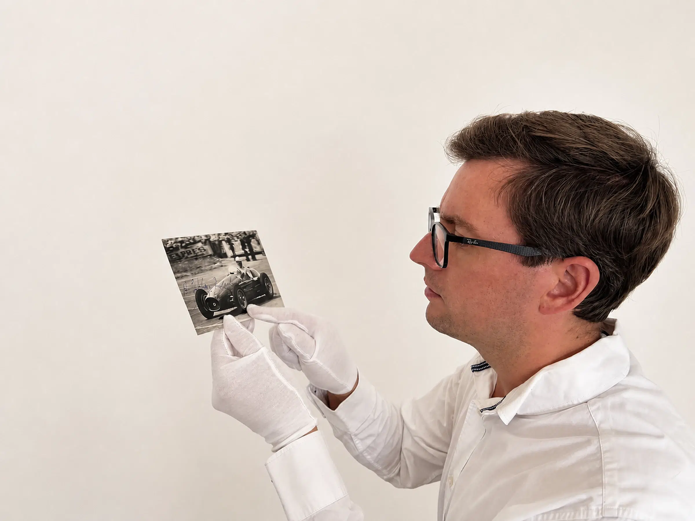 Alex Blackledge examining a signed Formula One photograph in cotton gloves